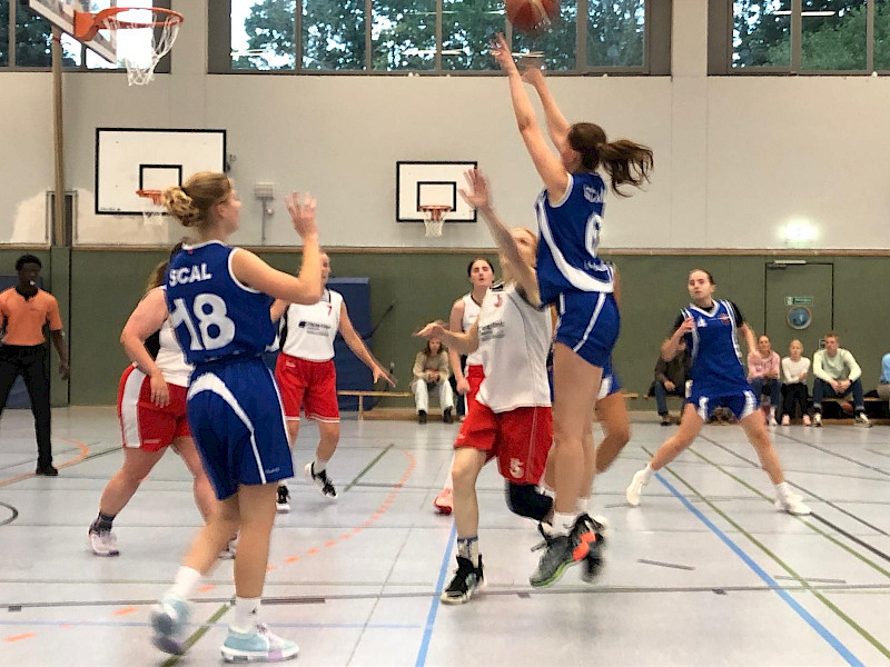 Spielerinnen auf dem Basketballcourt, blaue Trikots (SCAL) im Angriff gegen weiße Trikots (WSV)